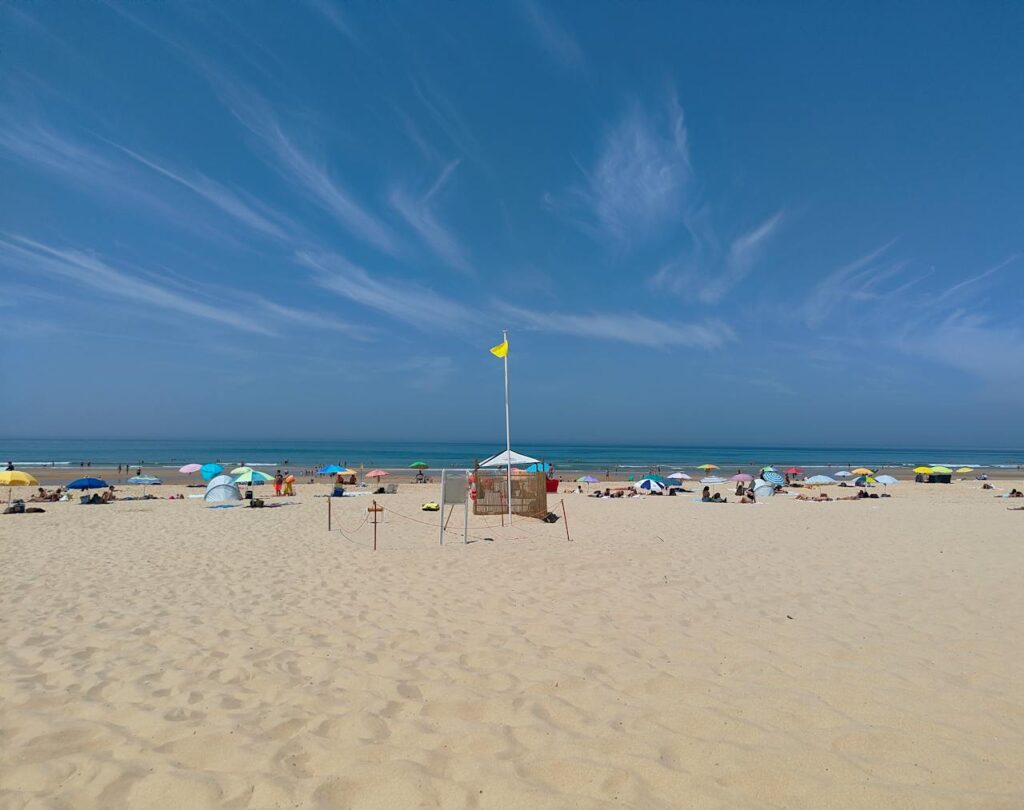 Beautiful sunny day at Costa da Caparica, Portugal, with vibrant beach umbrellas and a clear blue sky.